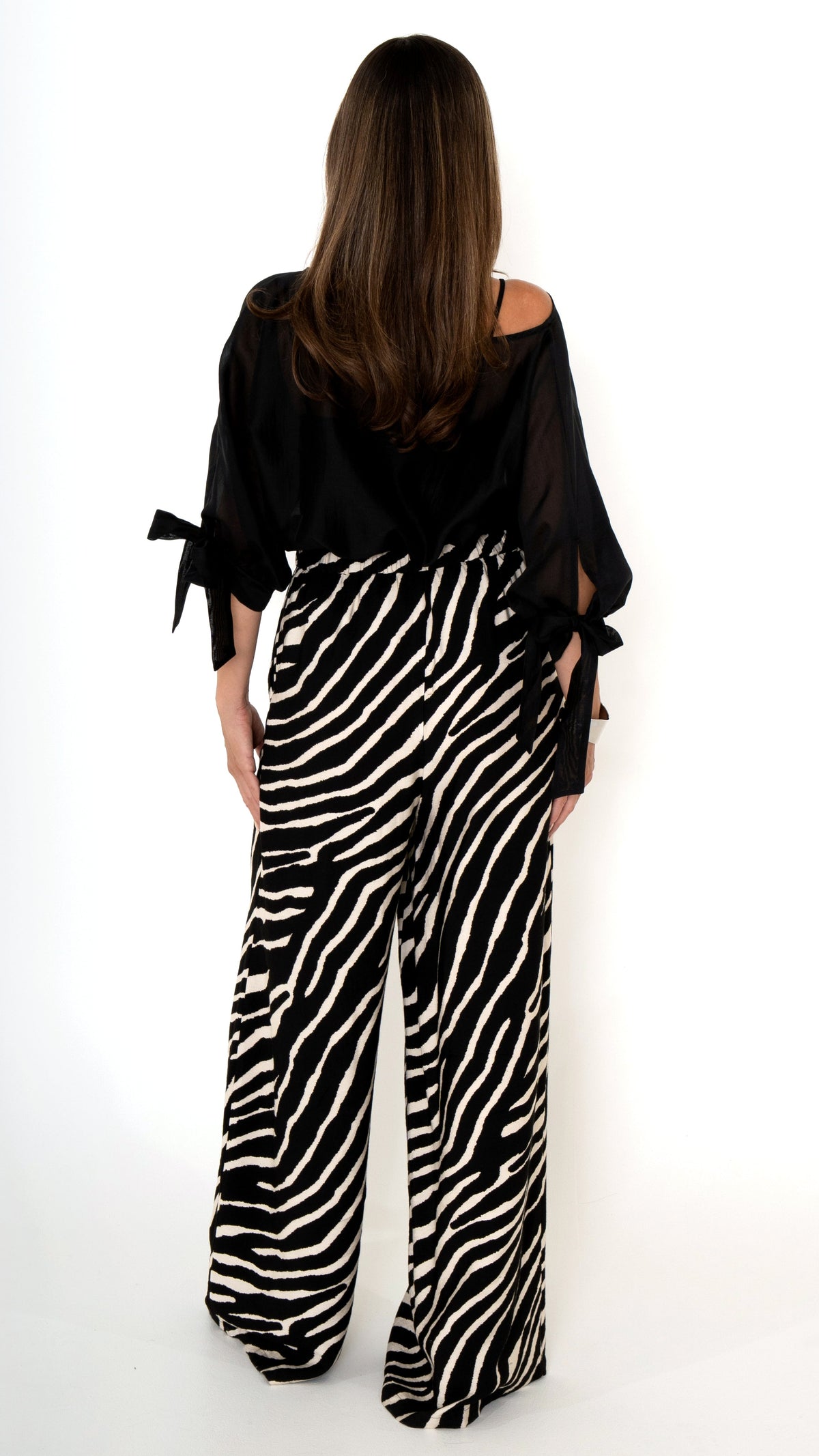 Rückansicht elegante ausgefallene Damenmode : weite lange Hose mit Zebra Animal Print und als Oberteil eine weite leicht transparente Chiffon Bluse mit Schleifen am Ärmel