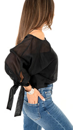 Seitenansicht Damemode: Cooles Outfit aus blauer Jeanshose und weite schwarze Bluse , halbtransparent und Schleifendetail am Ärmel