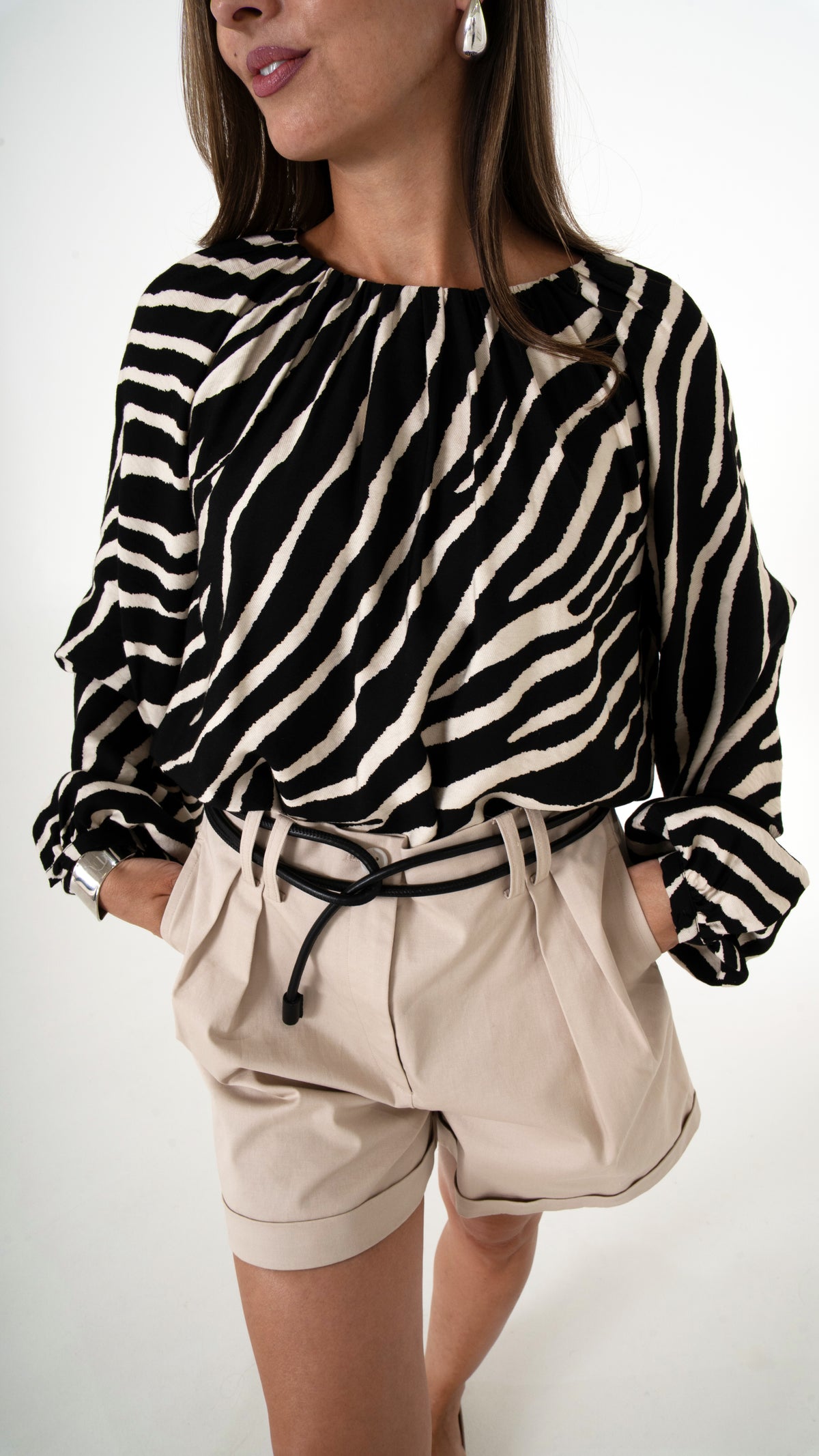 Detailansicht Elegante Damenmode für den Sommer mit animal Print: weite Bluse in Zebra Print mit Volumen Arm, kombiniert mit beiger weiter Shorts 
