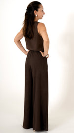 Rückansicht: Eine Dame mit dunklen Haaren trägt ein sommerlich schickes Outfit in der Farbe Mocca braun. Es besteht aus einer weiten lockeren Leinenhose mit elastischem Bund. Das Oberteil besteht aus einem Leinentop ohne Ärmel.