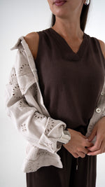 Detailansicht Anschnitt feminine Damenmode für den Sommer: Weite Denim Jacke mit floraler Lochstickerei in beige. Dazu eine Braune weite Hose und ein braunes Top mit V-Ausschnitt