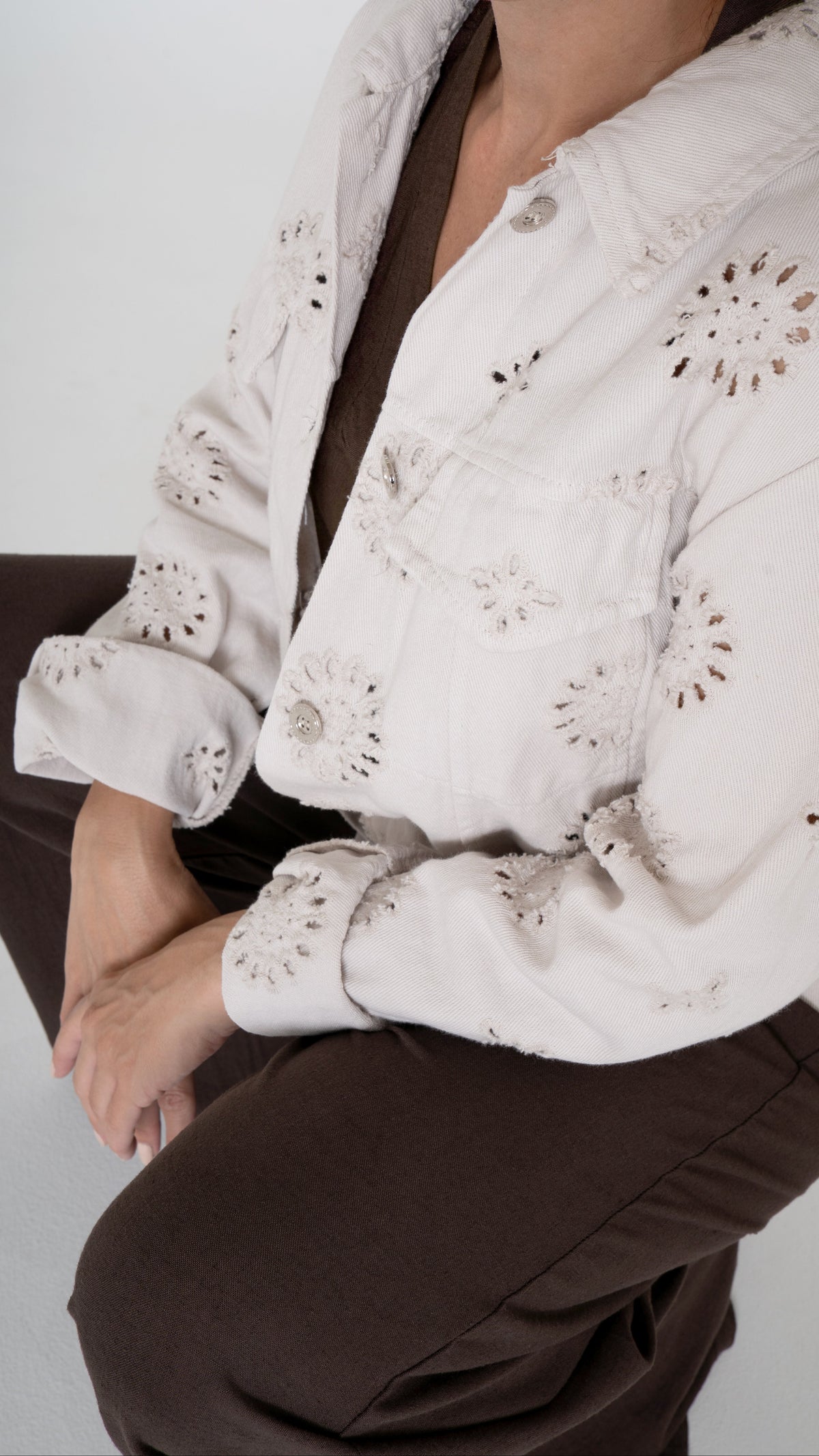 Detailansicht Anschnitt feminine Damenmode für den Sommer: Weite Denim Jacke mit floraler Lochstickerei in beige. Dazu eine braune weite Hose