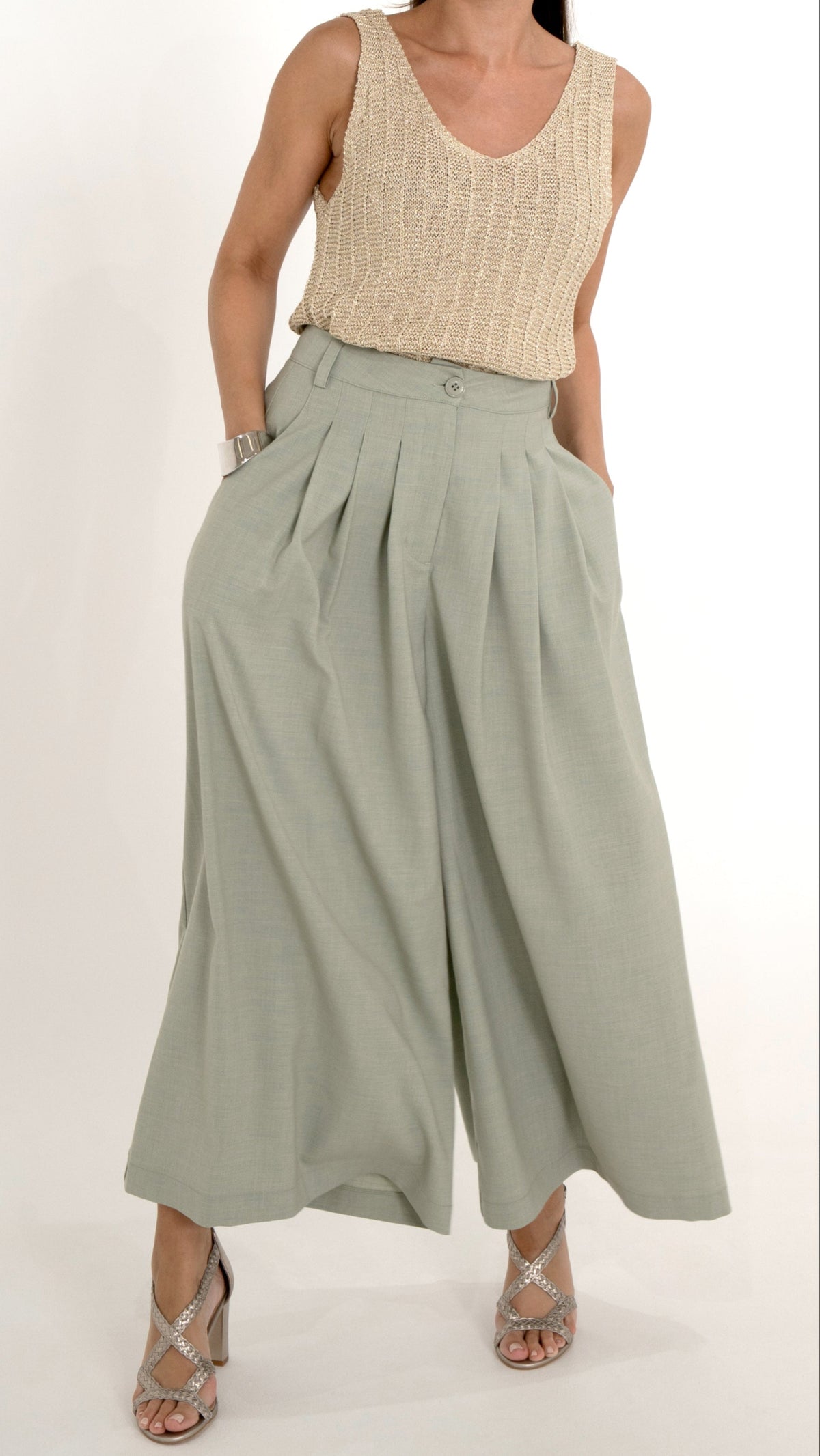 Ausgefallene Damenbekleidung mit einem  eleganten Sommeroutfit. Es besteht aus einer verkürzten Stoffhose mit Falten und extra weitem schwingenden Bein, in einem hellen Maigrün. Das Oberteil ist ein goldenes Stricktop mit leichtem Glanz, ohne Ärmel